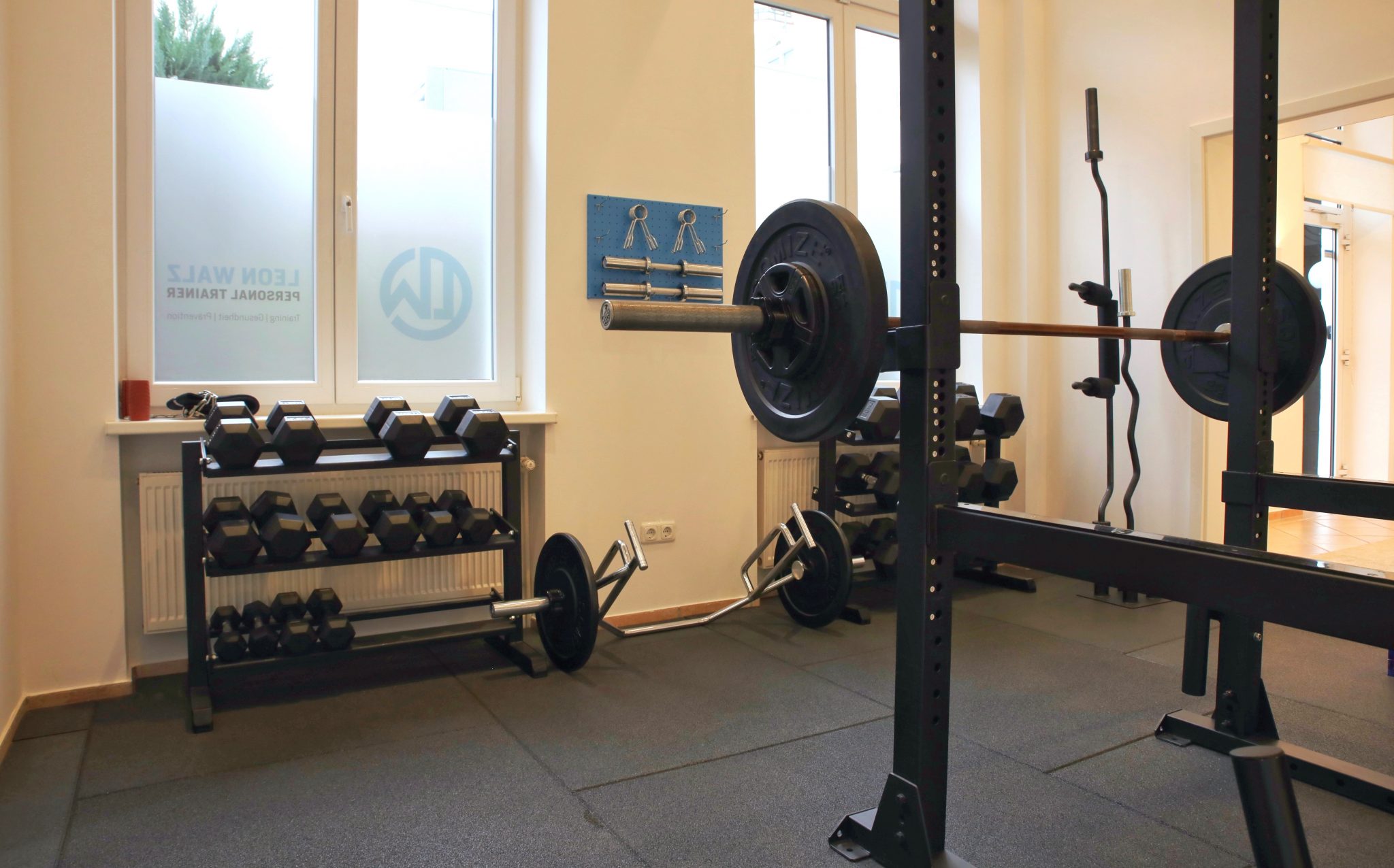Studio mit Squat-Rack und beschrifteter Fensterfront von Leon Walz.